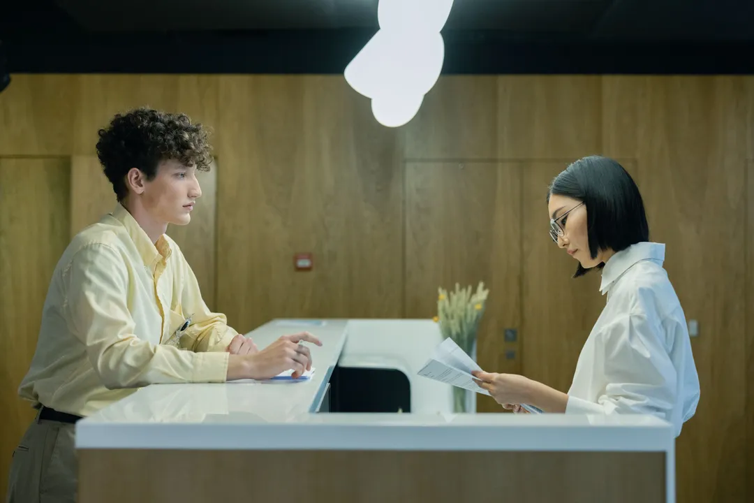 A recruitment consultant reviewing documents with a candidate at an elegant front desk